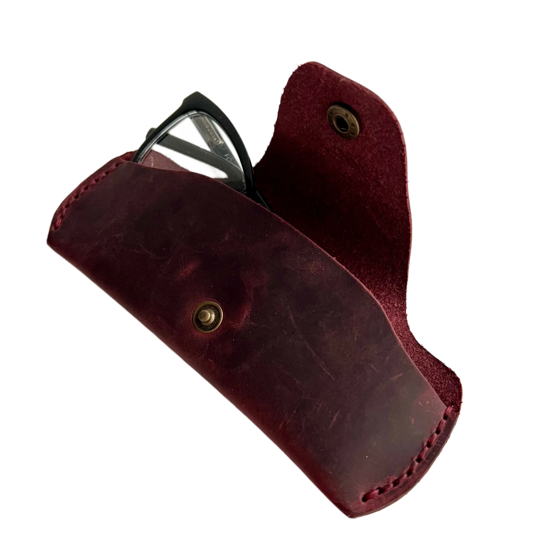 Small Soft Leather Eye Glasses Case in Burgundy, angled view with black-framed eyeglasses tucked inside