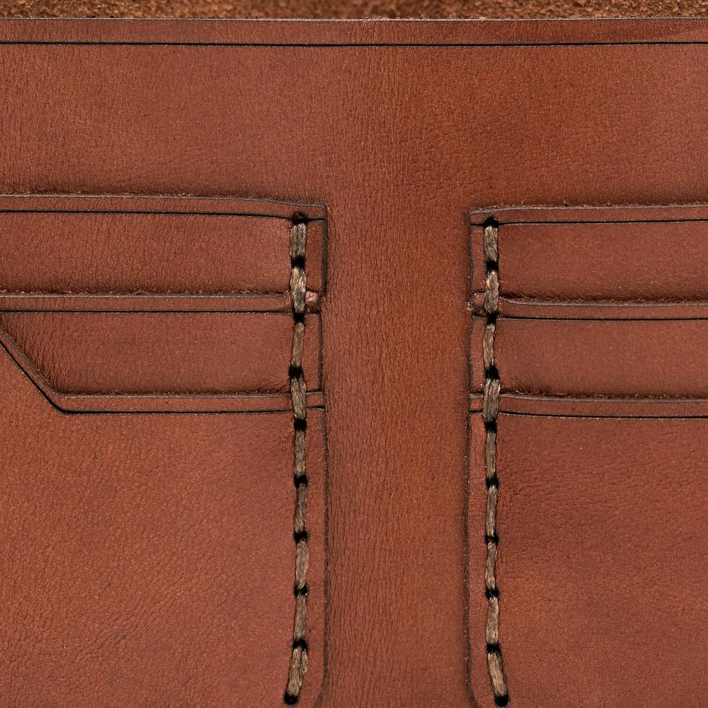 Handmade medium brown leather bifold wallet, close-up of leather texture and stitching